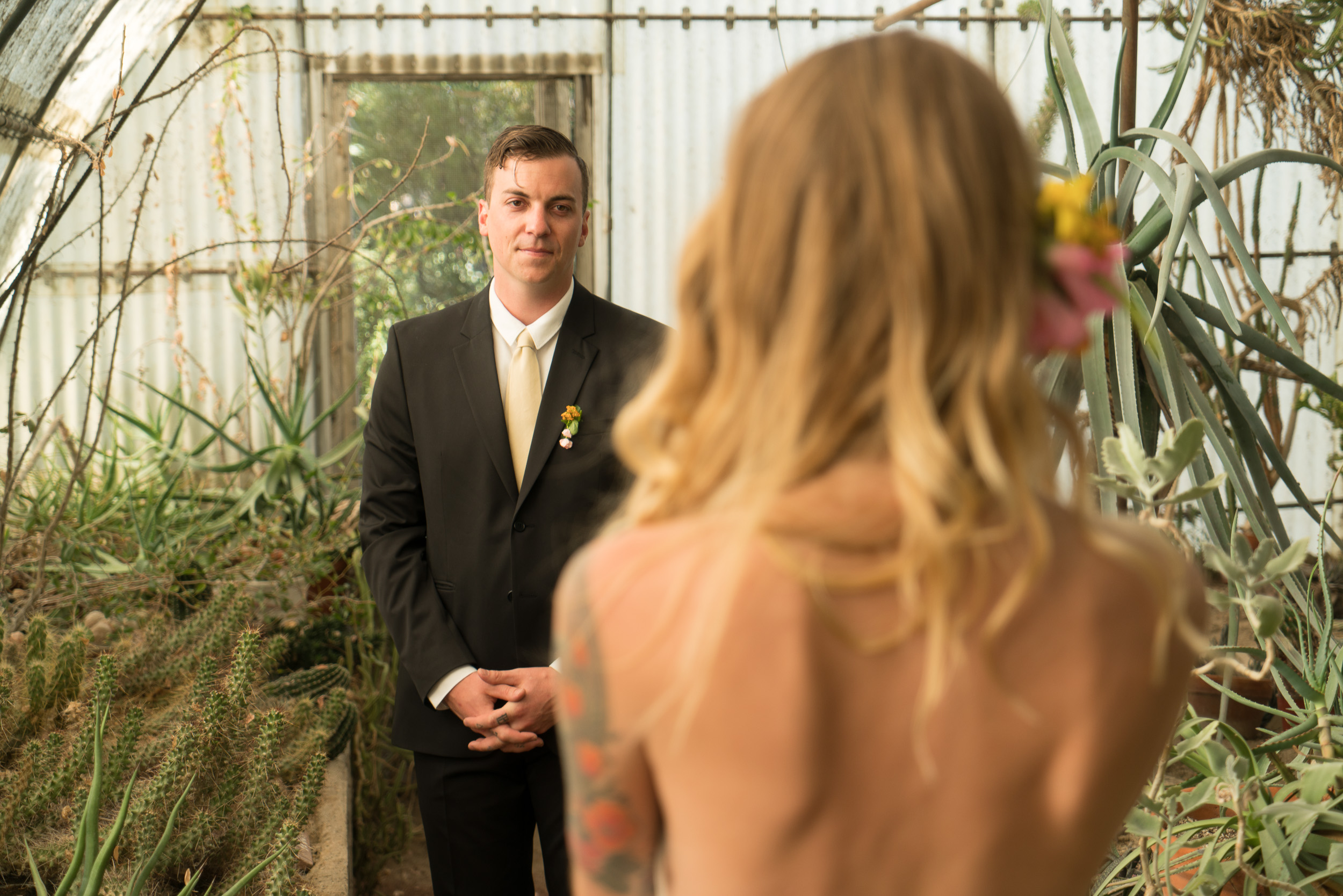 Groom waiting, bride walking toward him through the garden