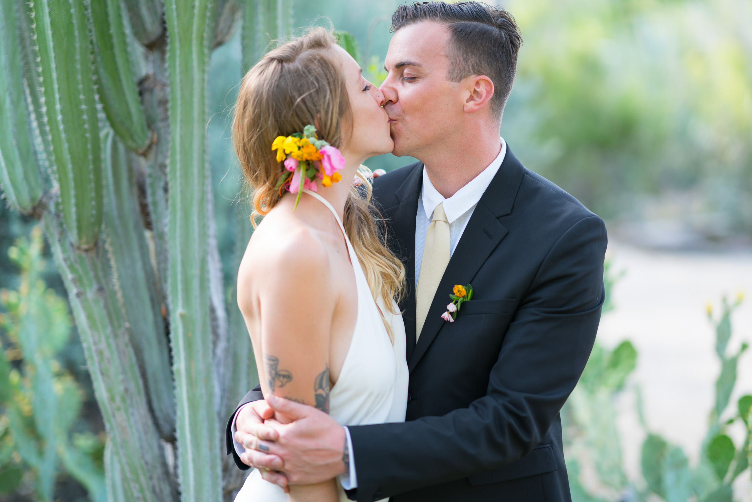 Couple kissing in front of tall cacti, warm afternoon light