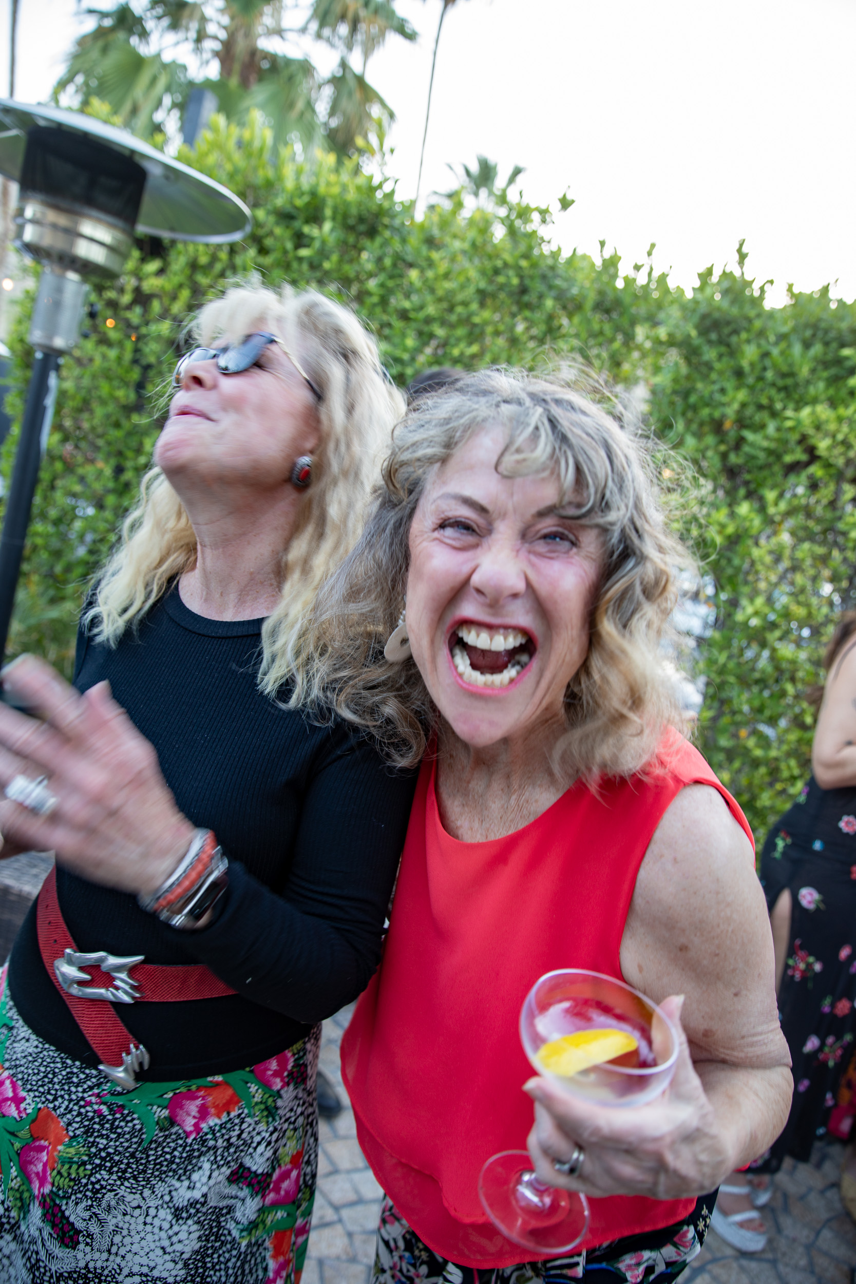 Two women laughing hard, one throwing her head back