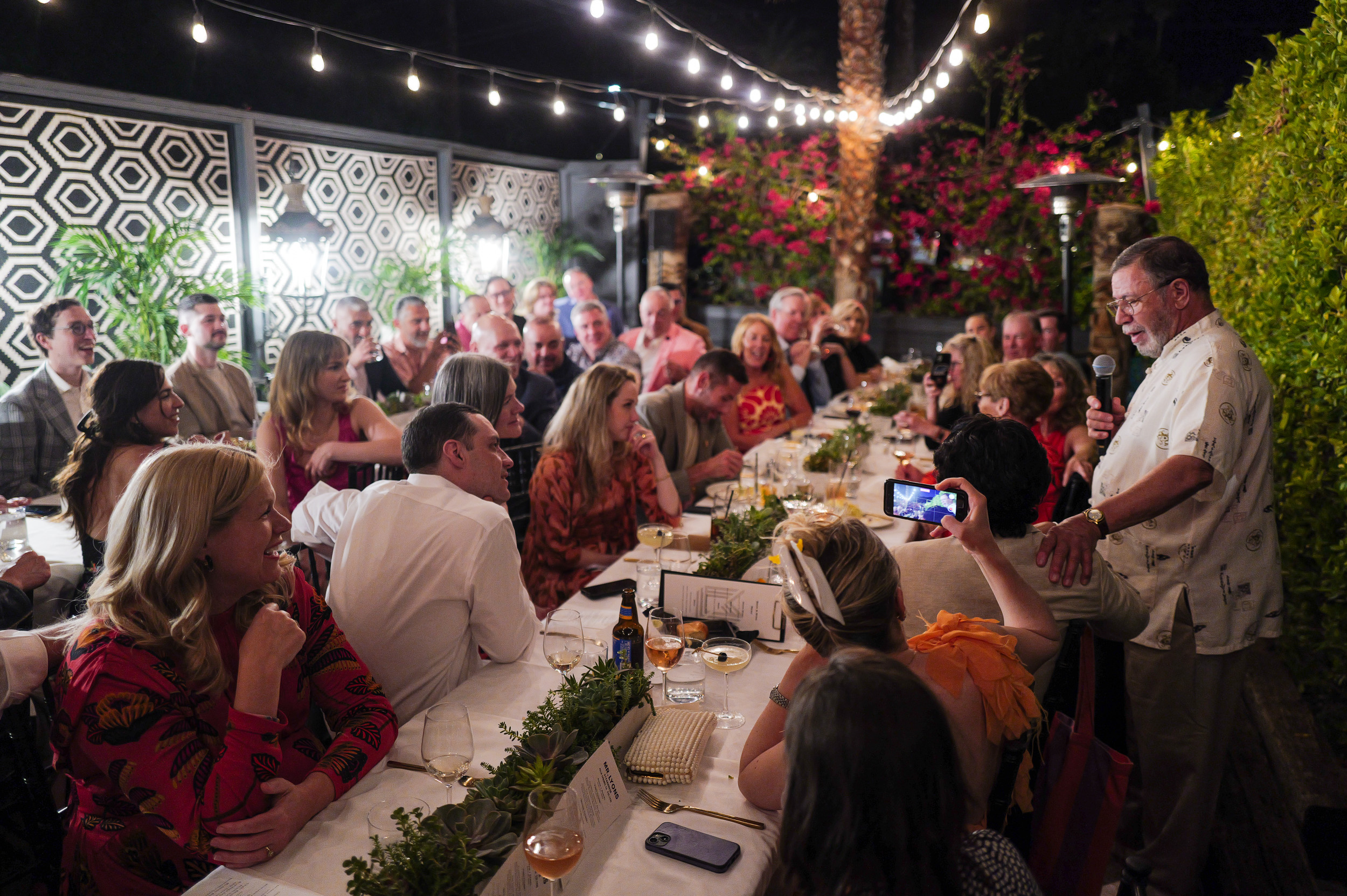 Full room view, outdoor dinner reception in full swing, bougainvillea walls