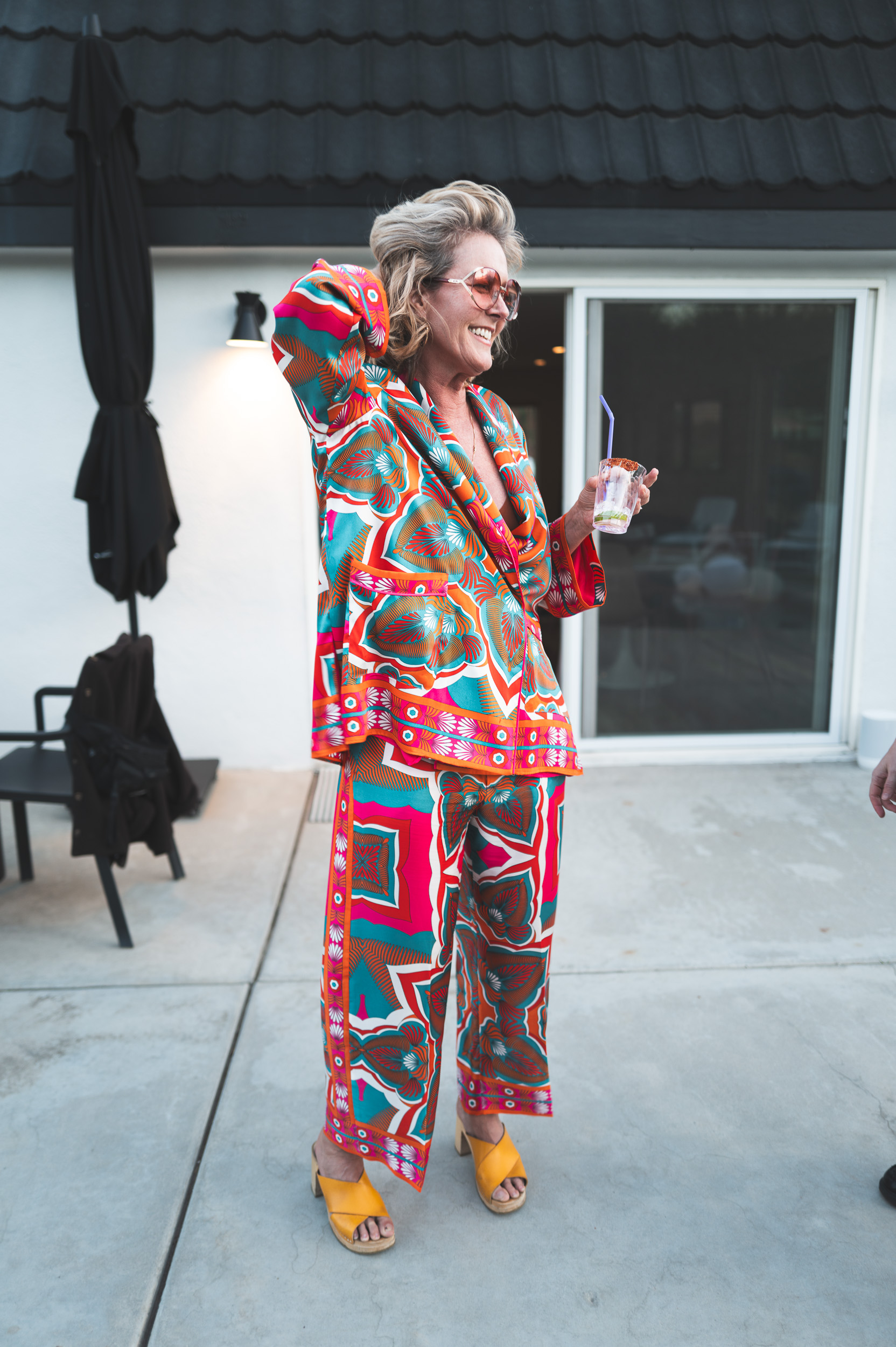 Guest in vibrant colorful outfit, holding a drink