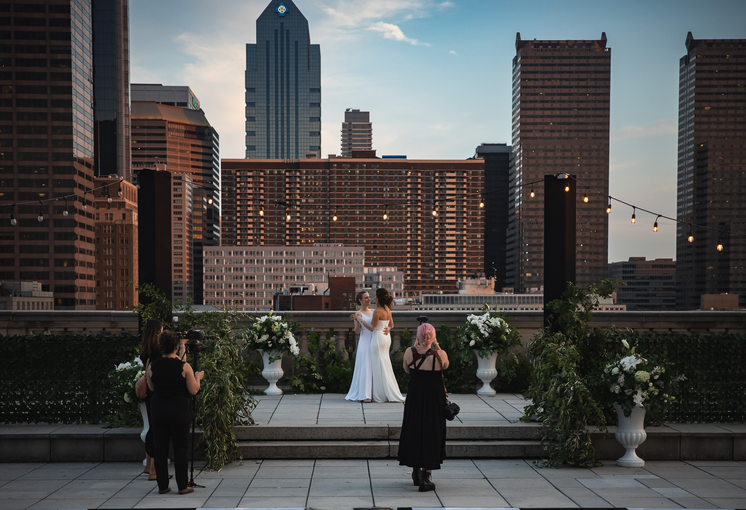 Rooftop ceremony, wide shot, city skyline backdrop